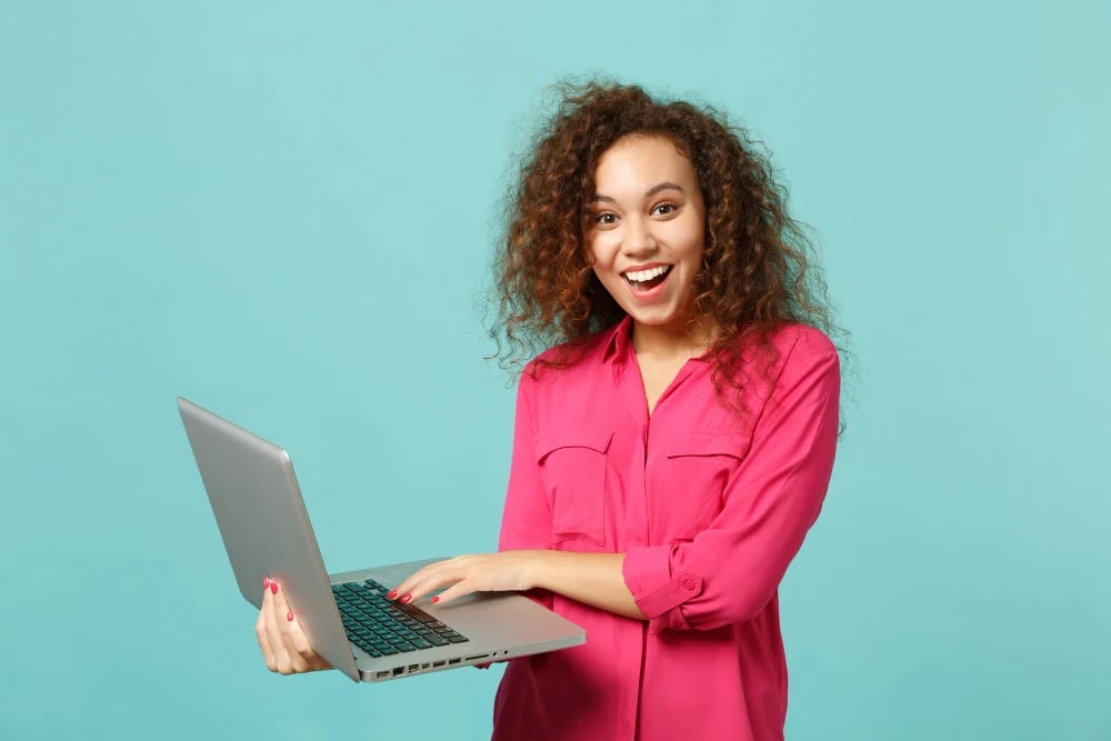 portrait-excited-african-girl-pink-casual-clothes-using-laptop-pc-computer-isolated-blue-turquoise-wall-background-studio-people-sincere-emotions-lifestyle-concept-mock-up-copy-space